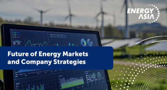 Landscape with wind turbines and solar panels; foreground screen displaying complex graphs and data.
